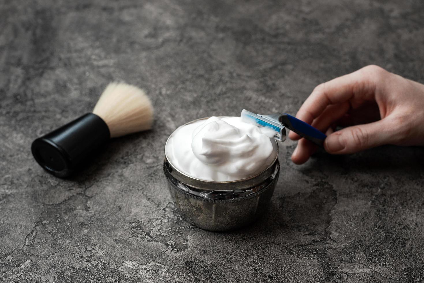 Hand holds disposable razor on gray wall background photo
