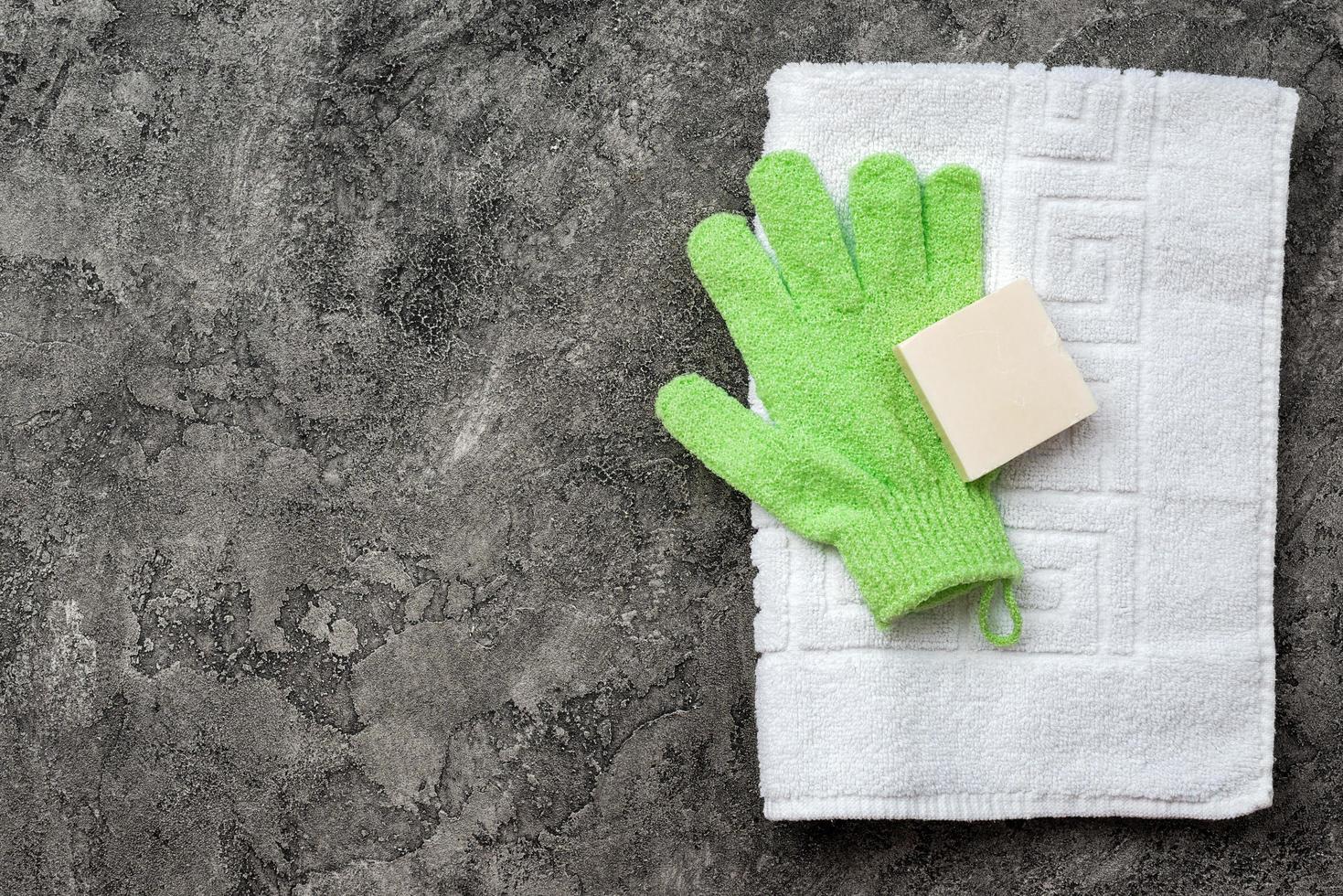 Soap, shower towel, bath mitten on gray, plaster flat lay background with copy space. Hygiene concept. photo