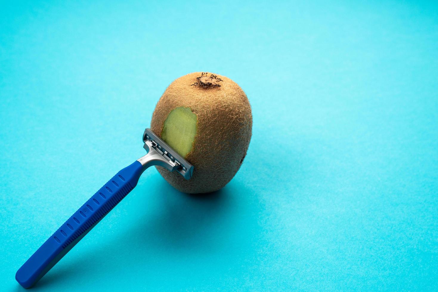 Kiwi fruit and razor on white background. Hair removal concept. Creative minimal concept with copy space. photo