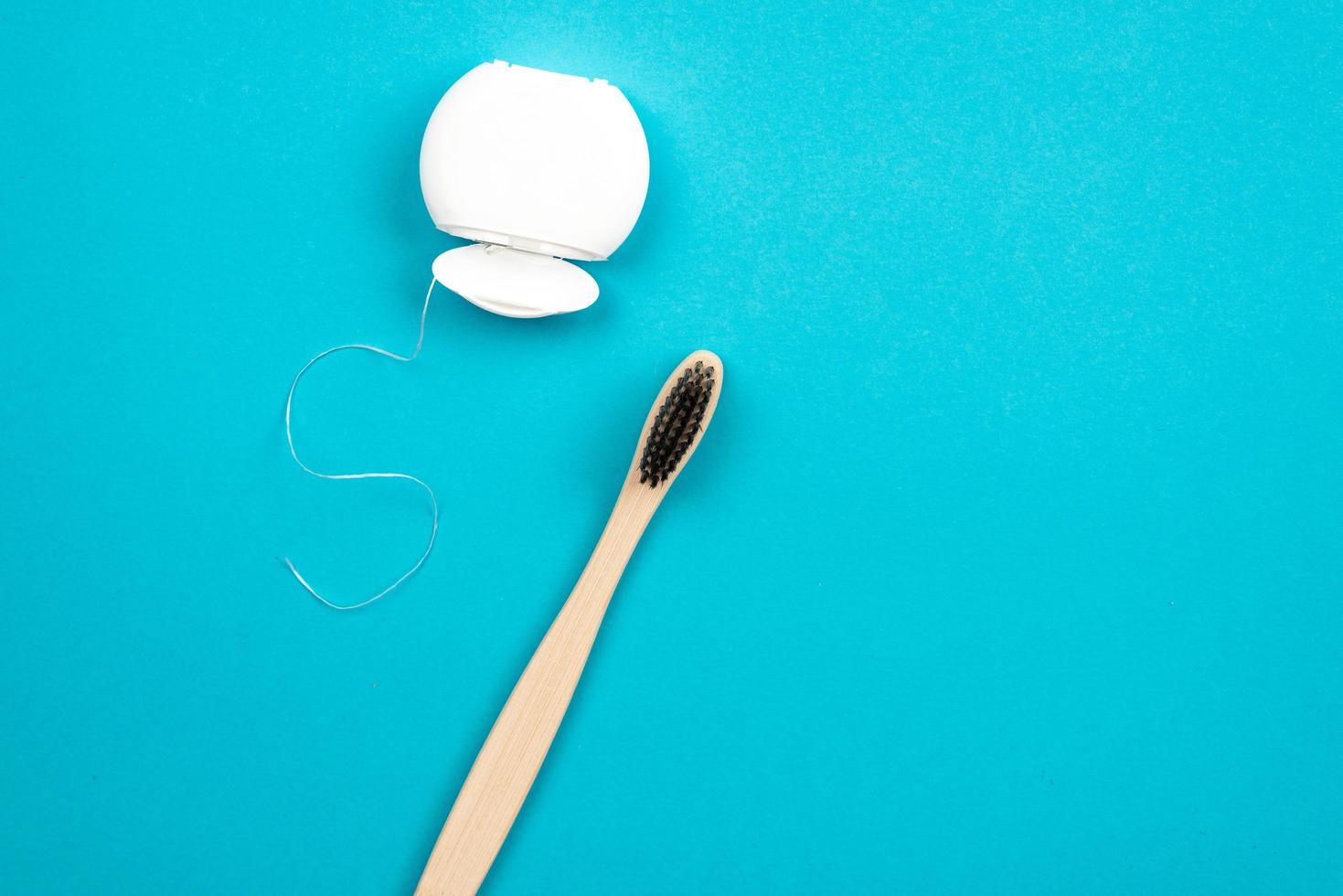 Cepillo de dientes e hilo dental sobre fondo azul. foto