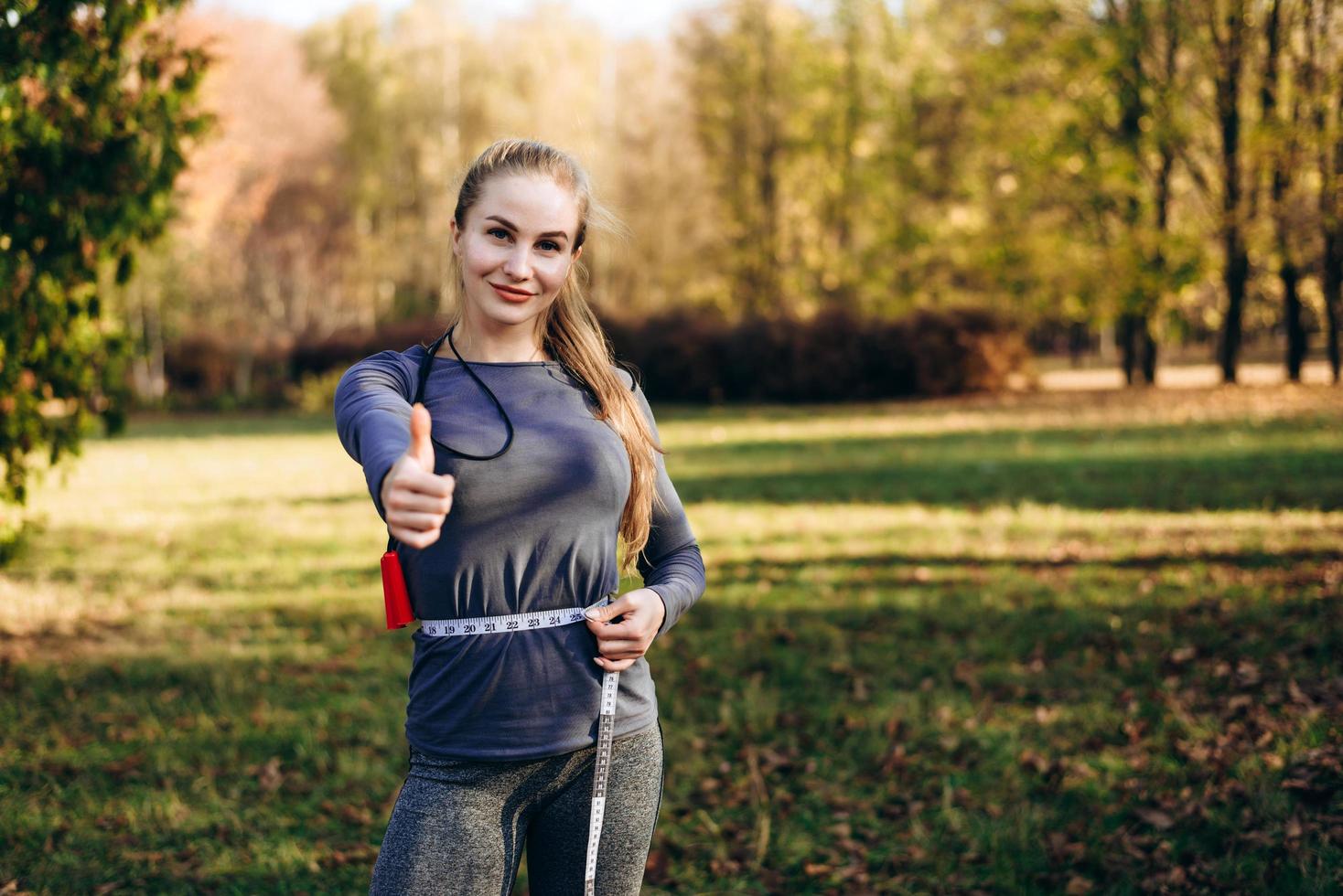 Mujer joven sentirse feliz midiendo su cintura después del entrenamiento foto