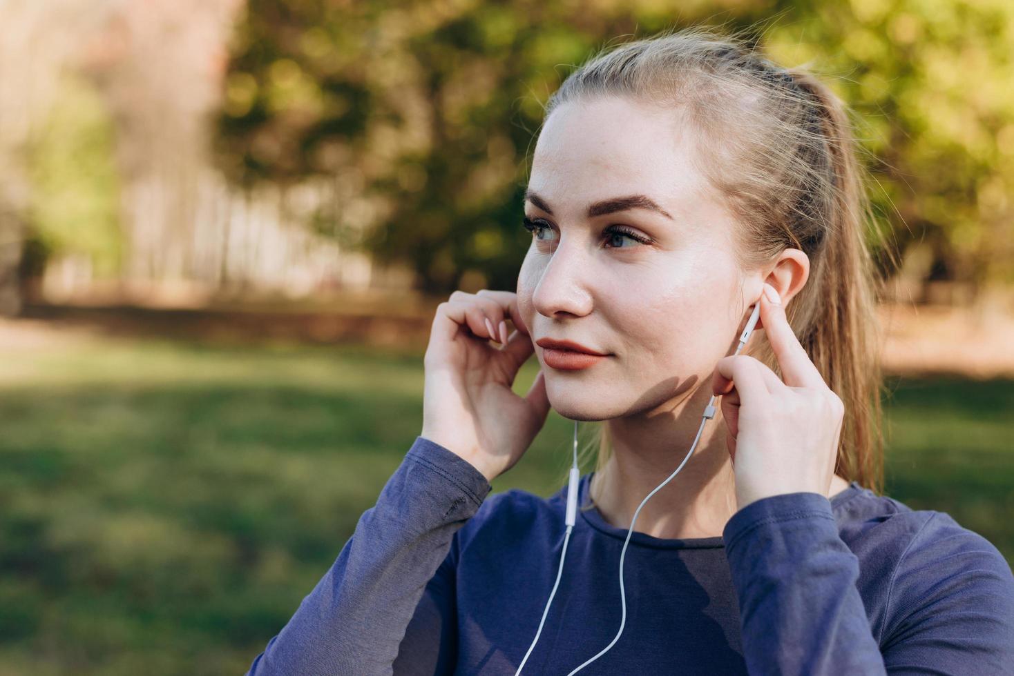 Chica deportiva en auriculares se ajusta al entrenamiento. foto