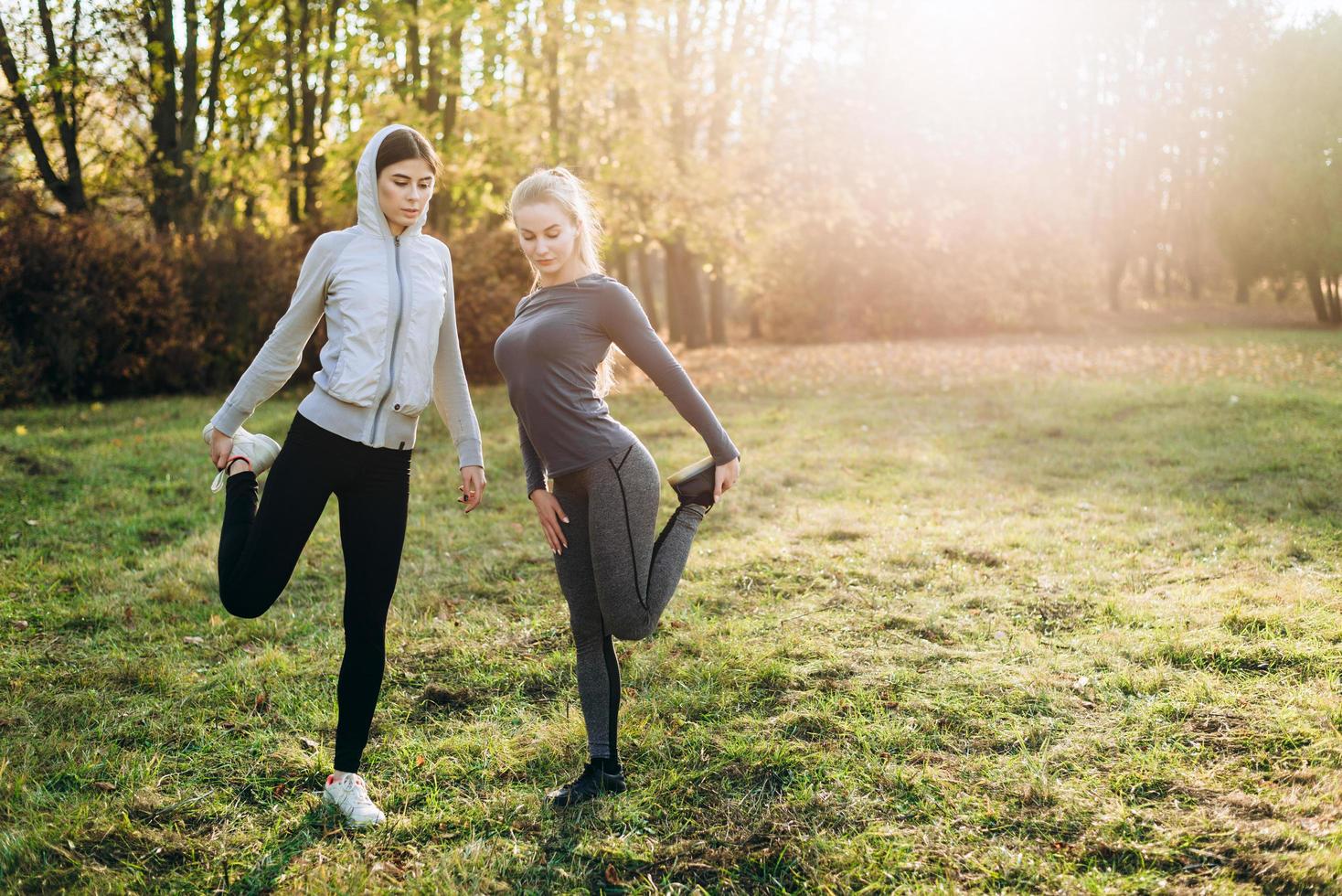 Two cute girlfriends do stretching before training outdoors. photo