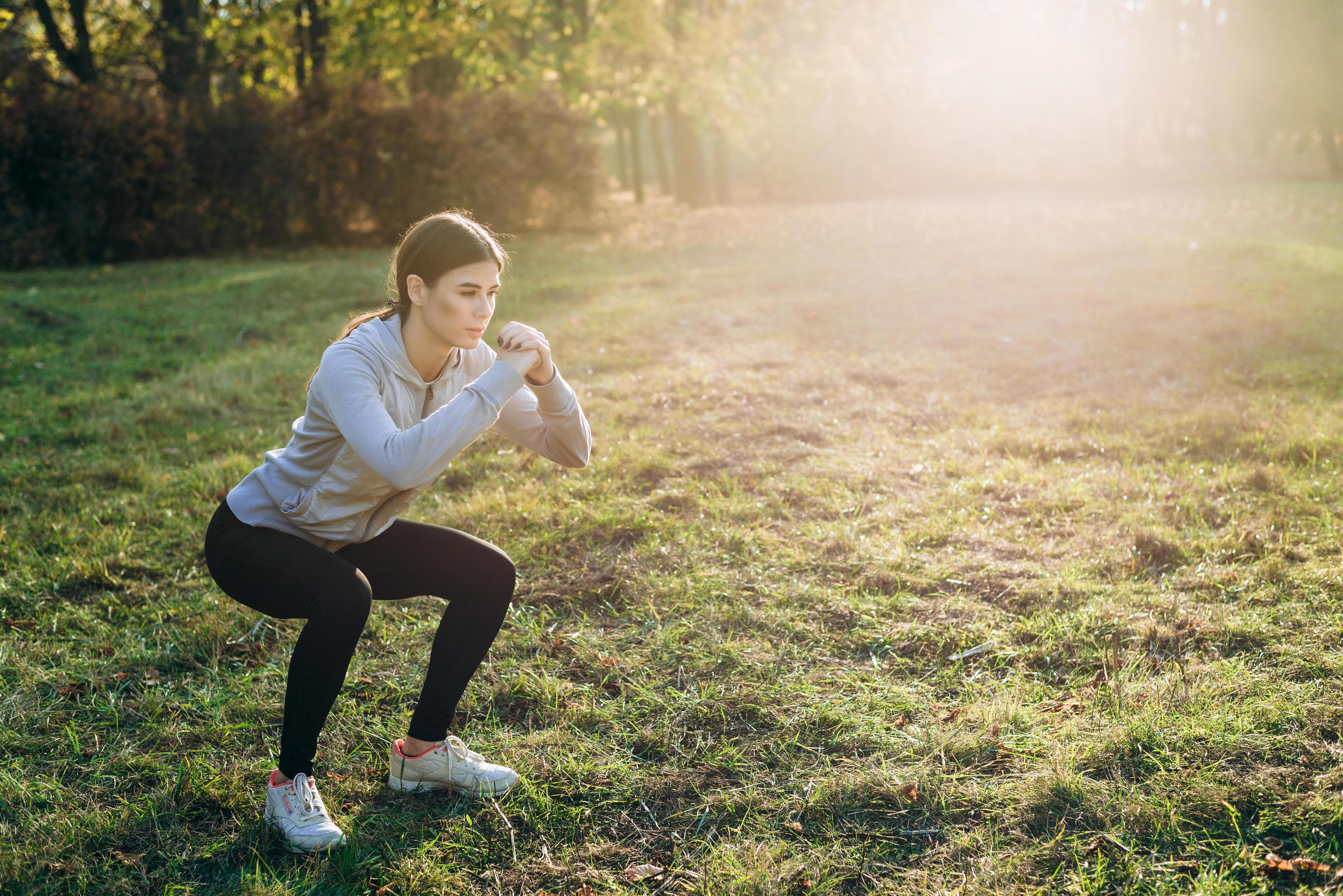 entrena afuera, chica guapa entrena en el parque, hace sentadillas