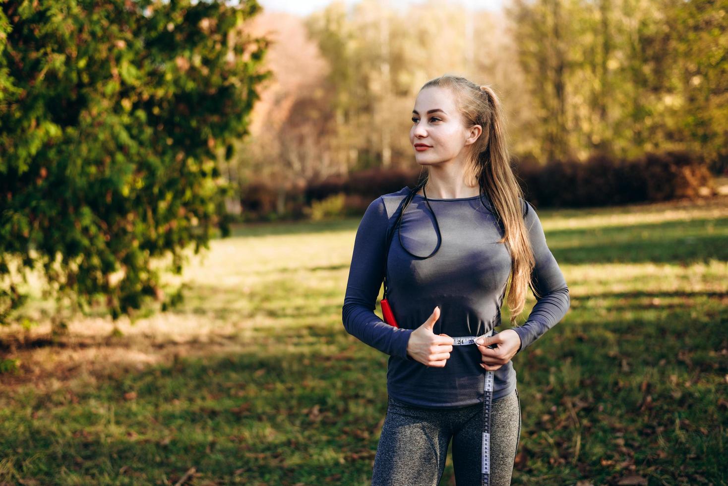 hermosa chica en el parque de otoño mide su cintura, mirando a otro lado. foto