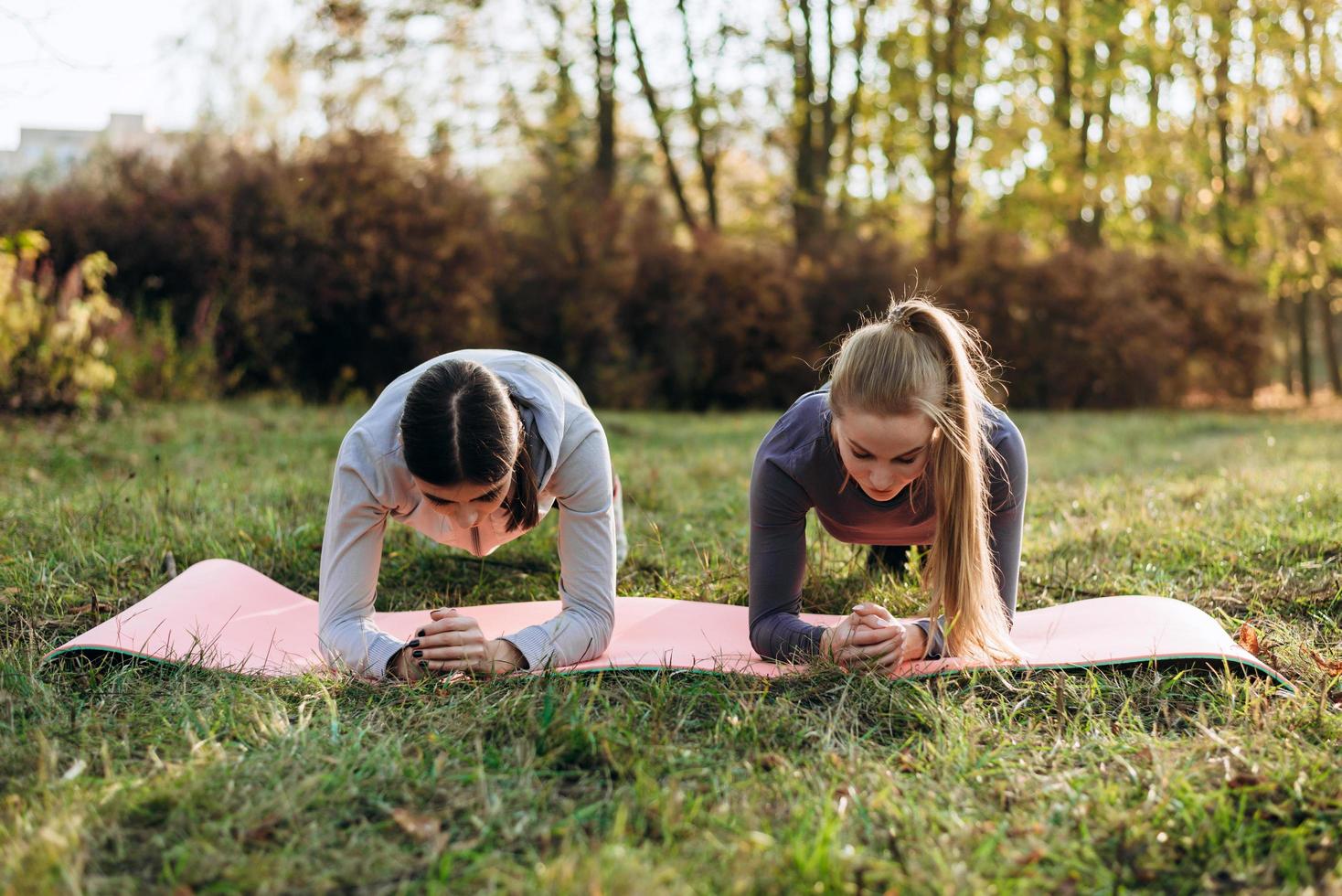 Two girlfriends are doing fitness plank in the park. photo