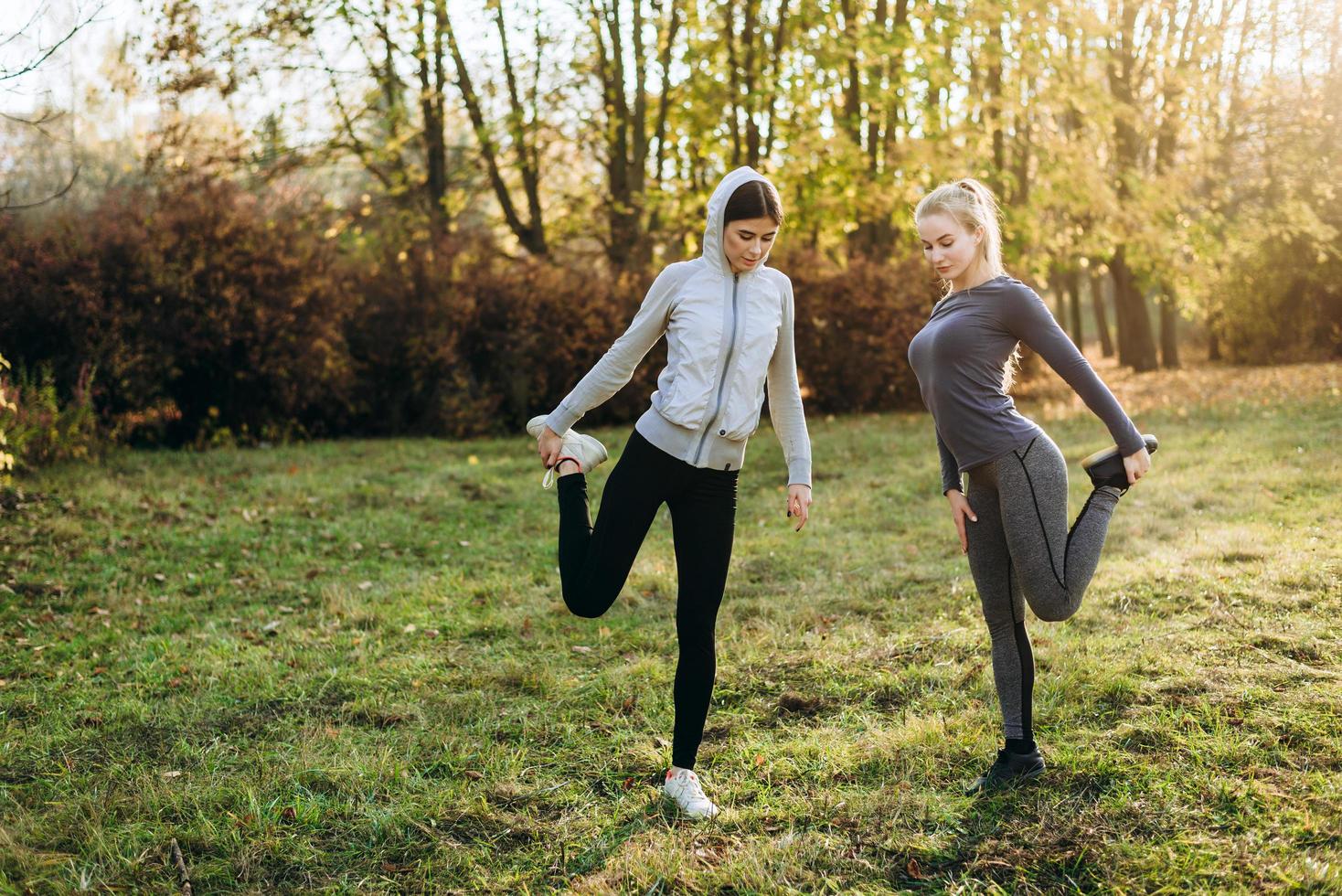 Morning fitness in the park. Two young girls are doing exercises. photo