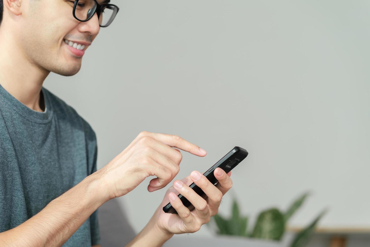 Primer plano de un hombre feliz usando un teléfono inteligente, búsqueda, navegación, redes sociales, mensaje, correo electrónico, marketing digital en Internet, compras en línea. foto