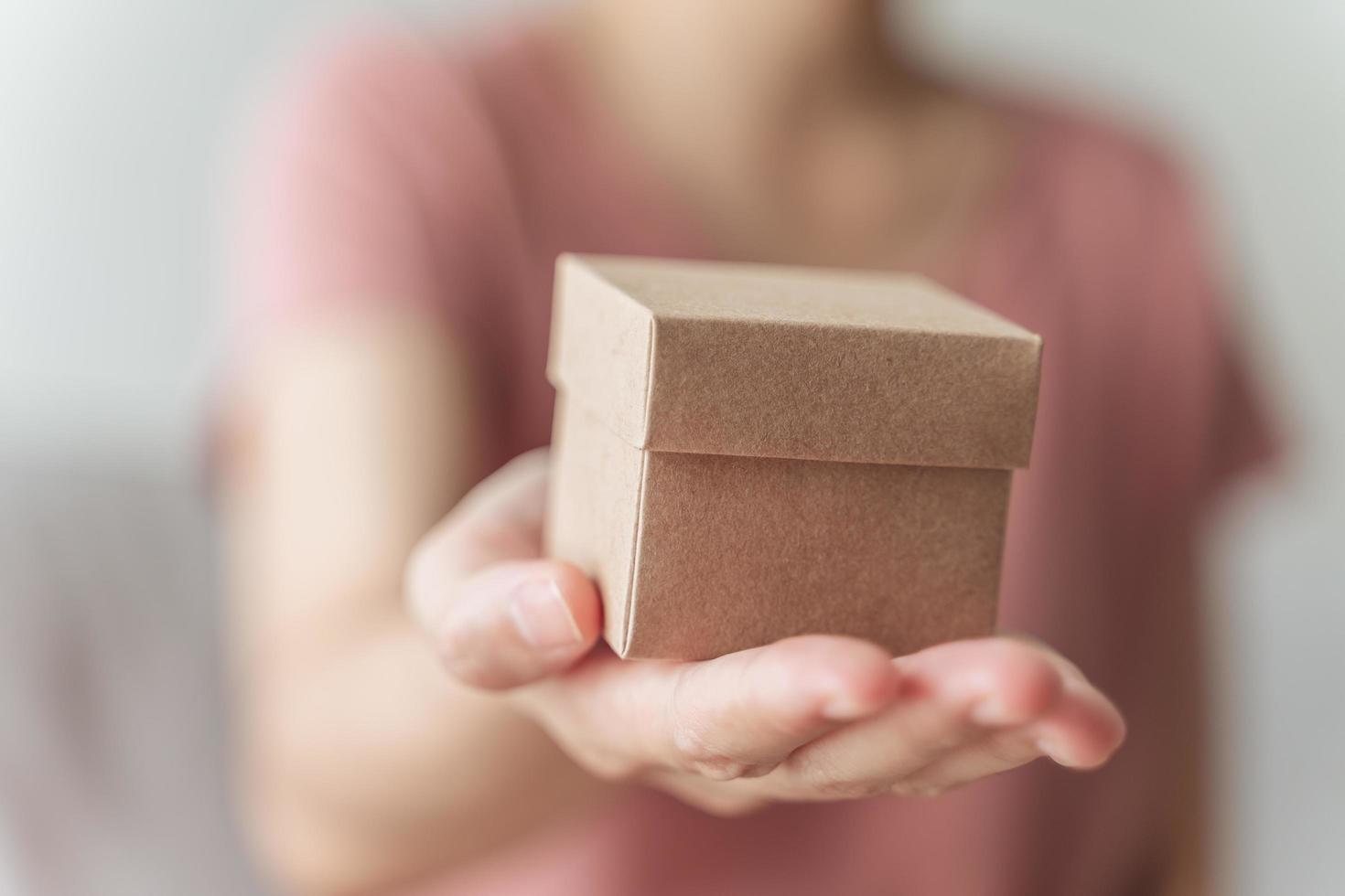 Cerca de manos de mujer sosteniendo una pequeña caja de regalo. pequeña caja de regalo en manos de la mujer. foto