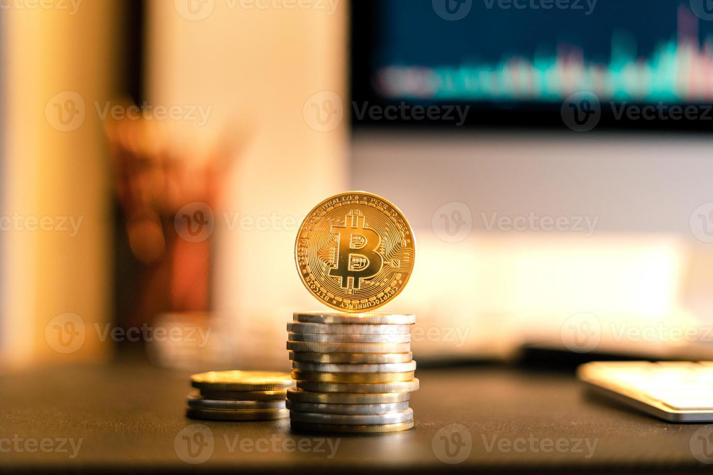 Bitcoin is placed on a desk in front of a computer graph photo