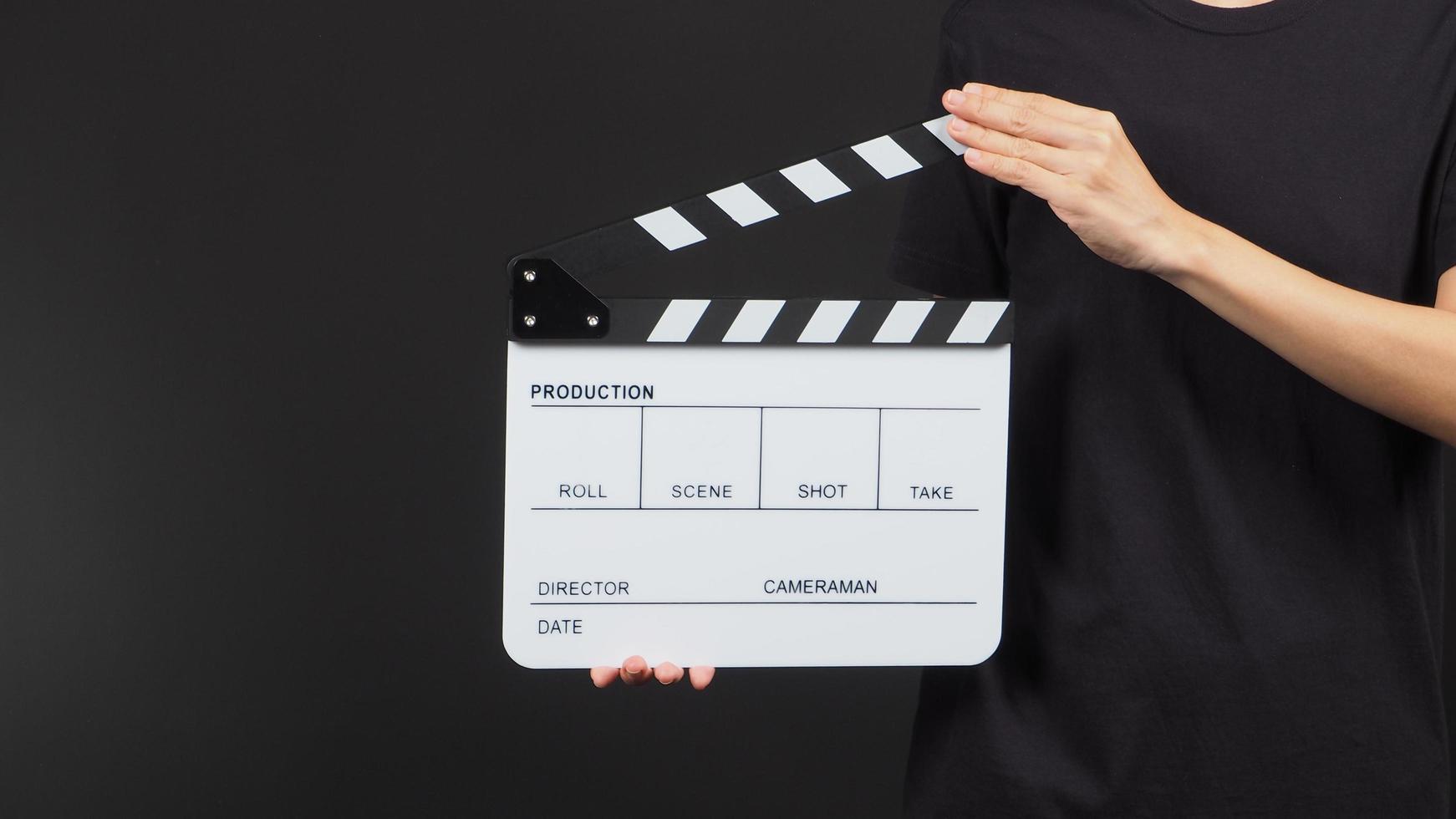 Hand is holding white clap board or movie slate use in video production and movie industry on black background. photo