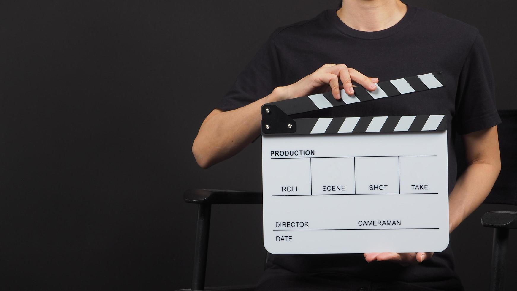 woman hand is holding white clap board or movie slate use in video production and movie industry on black background. photo