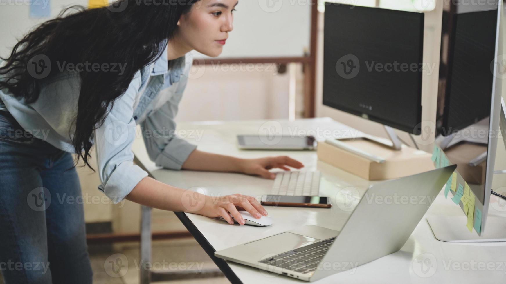 A female programmer bends down to use a computer to review a client presentation program. photo