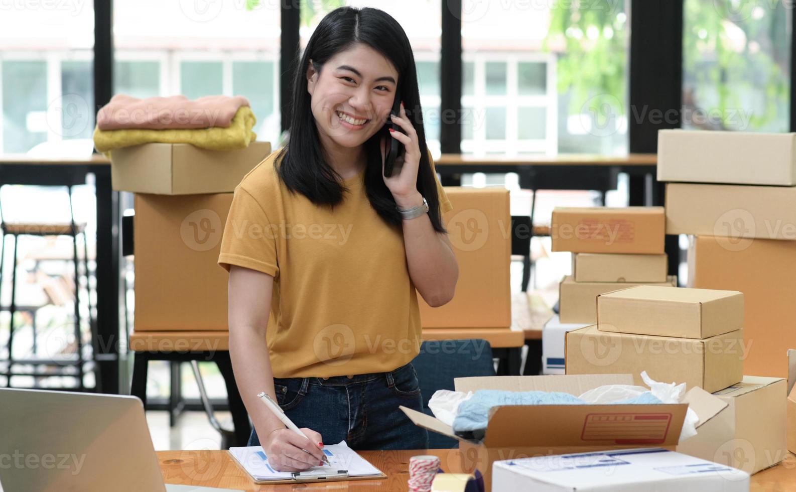 mujer vendedora en línea llama al teléfono y toma notas y toma pedidos con una sonrisa. foto