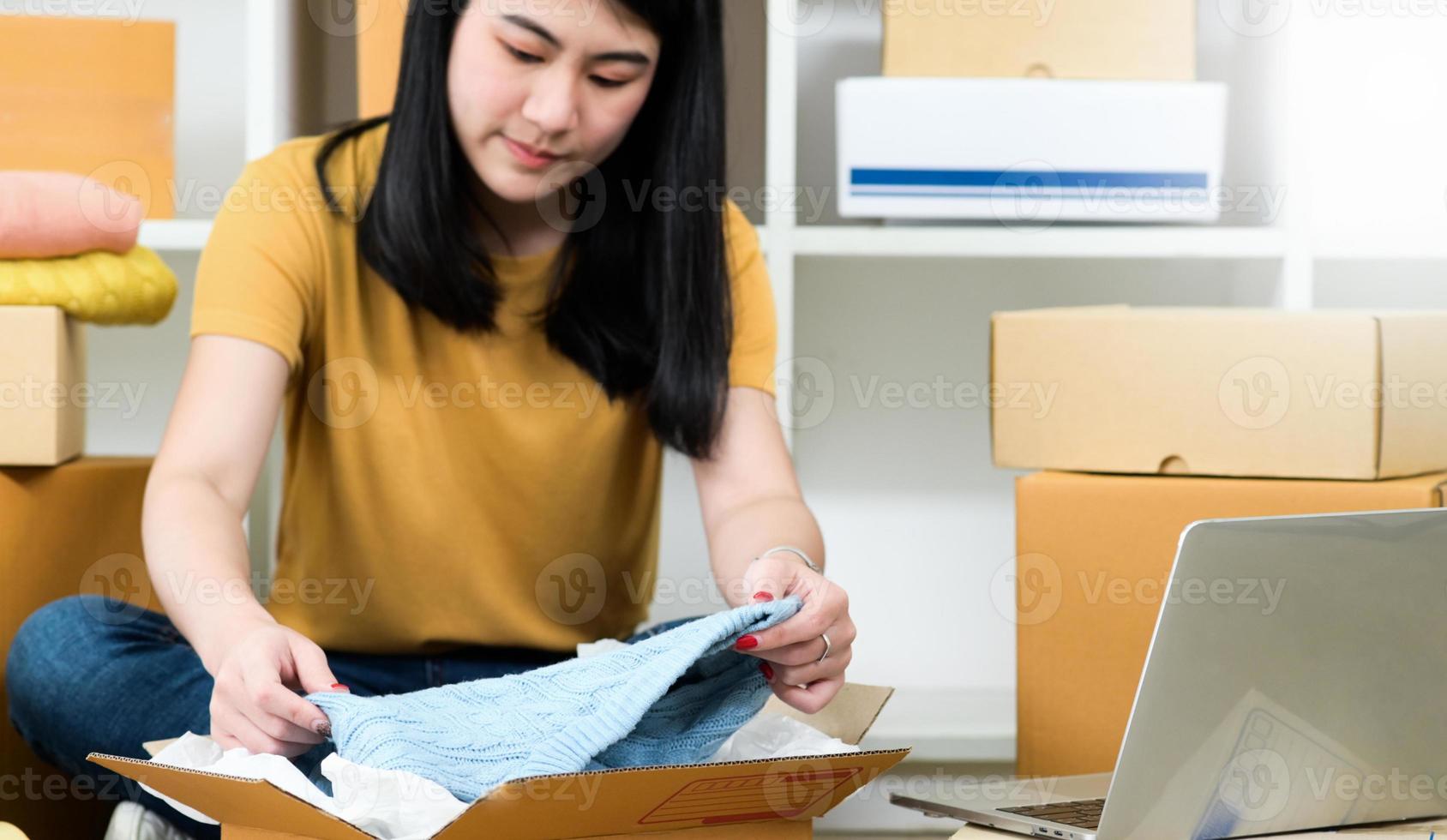 mujer empaca una camisa en una caja de paquetes para entregar a un cliente, vender productos en línea, transportar paquetes. foto