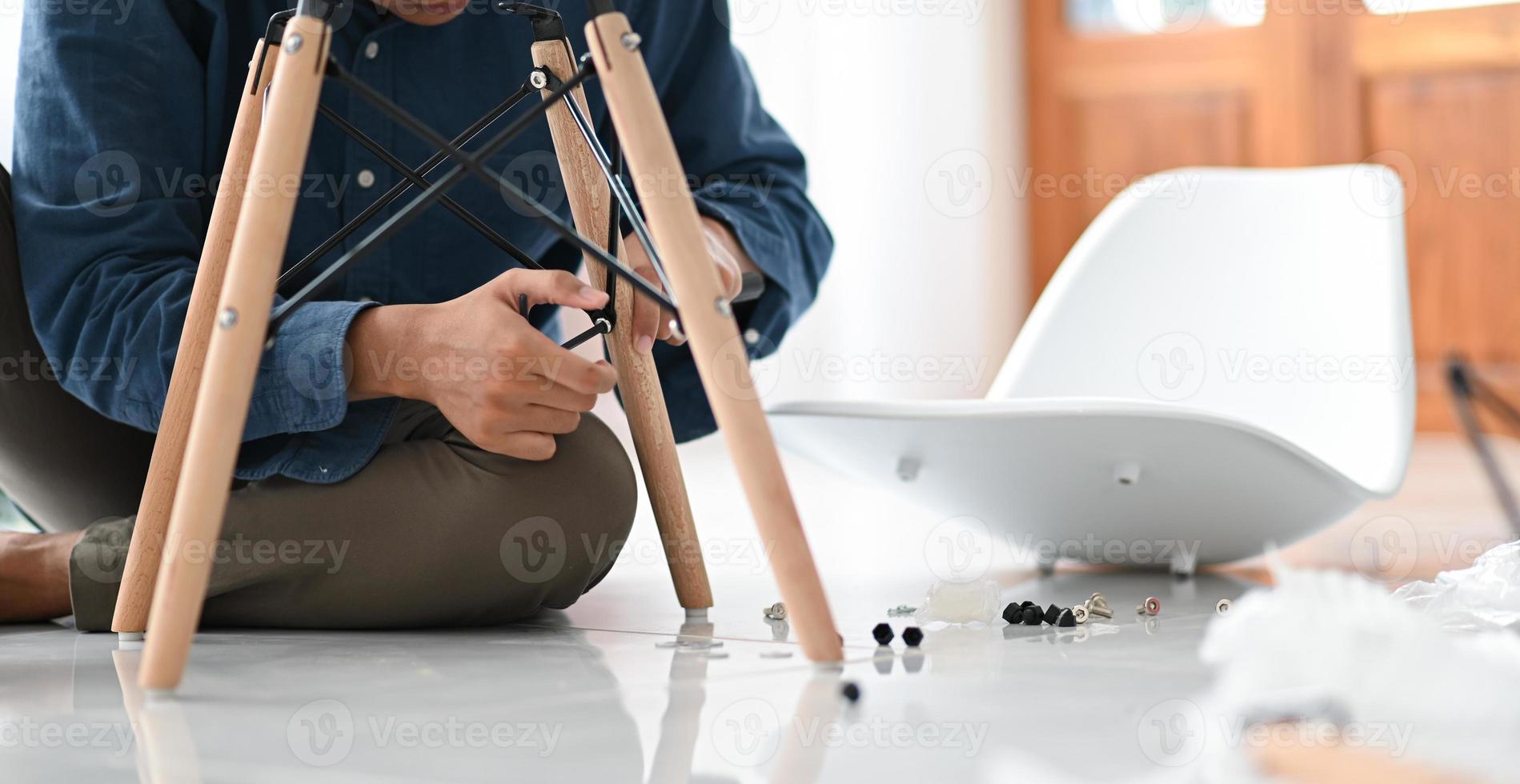 un joven monta una silla en la casa, repara la silla para su reutilización. foto