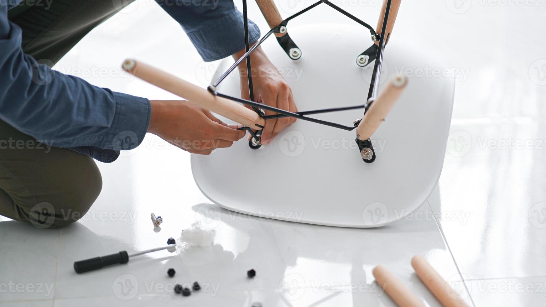 joven montando sillas, reparando sillas para su reutilización, bricolaje para el hogar para ahorrar dinero. foto