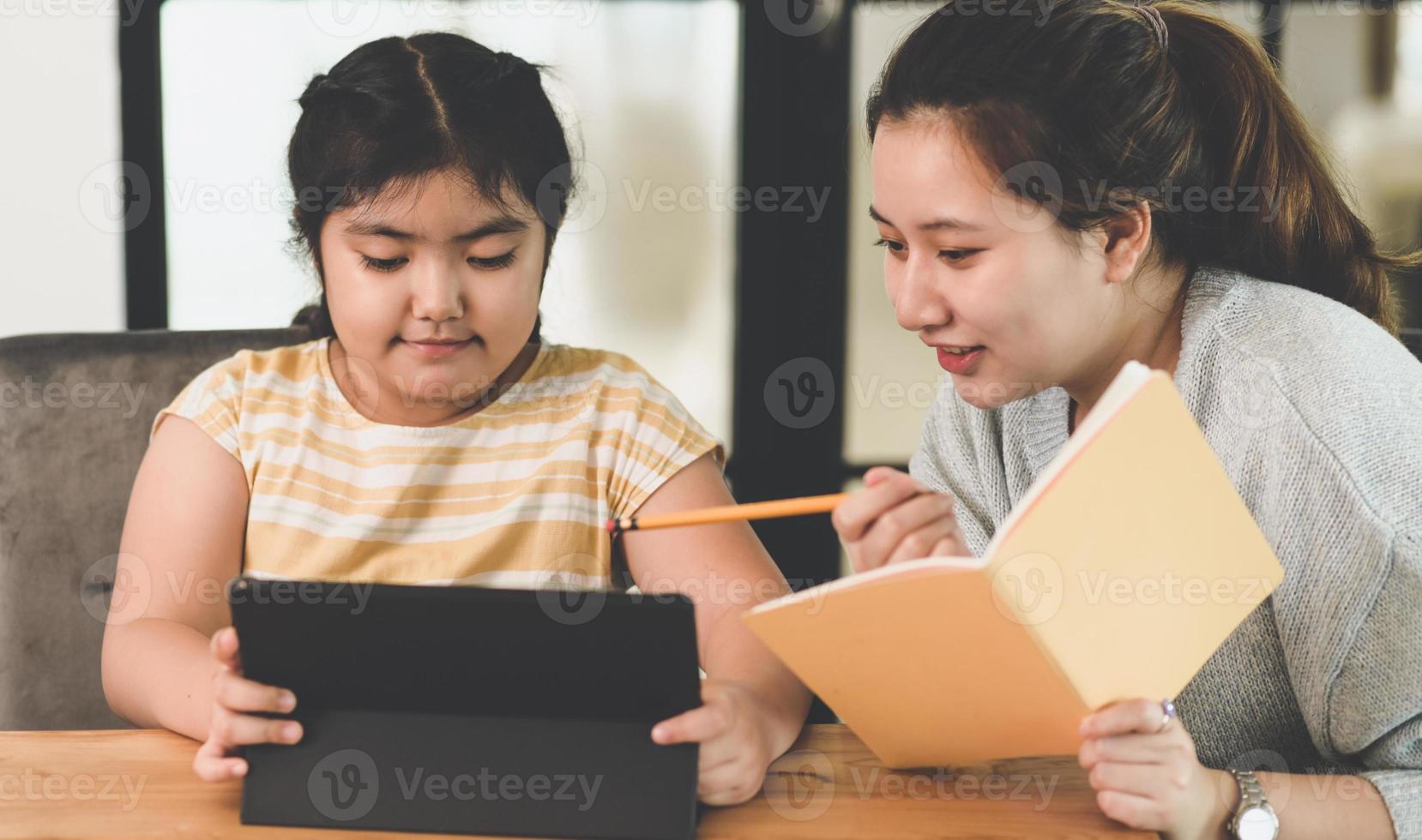 A child girl is studying with her teacher at home, teenage girls teaching girls homework at home. photo