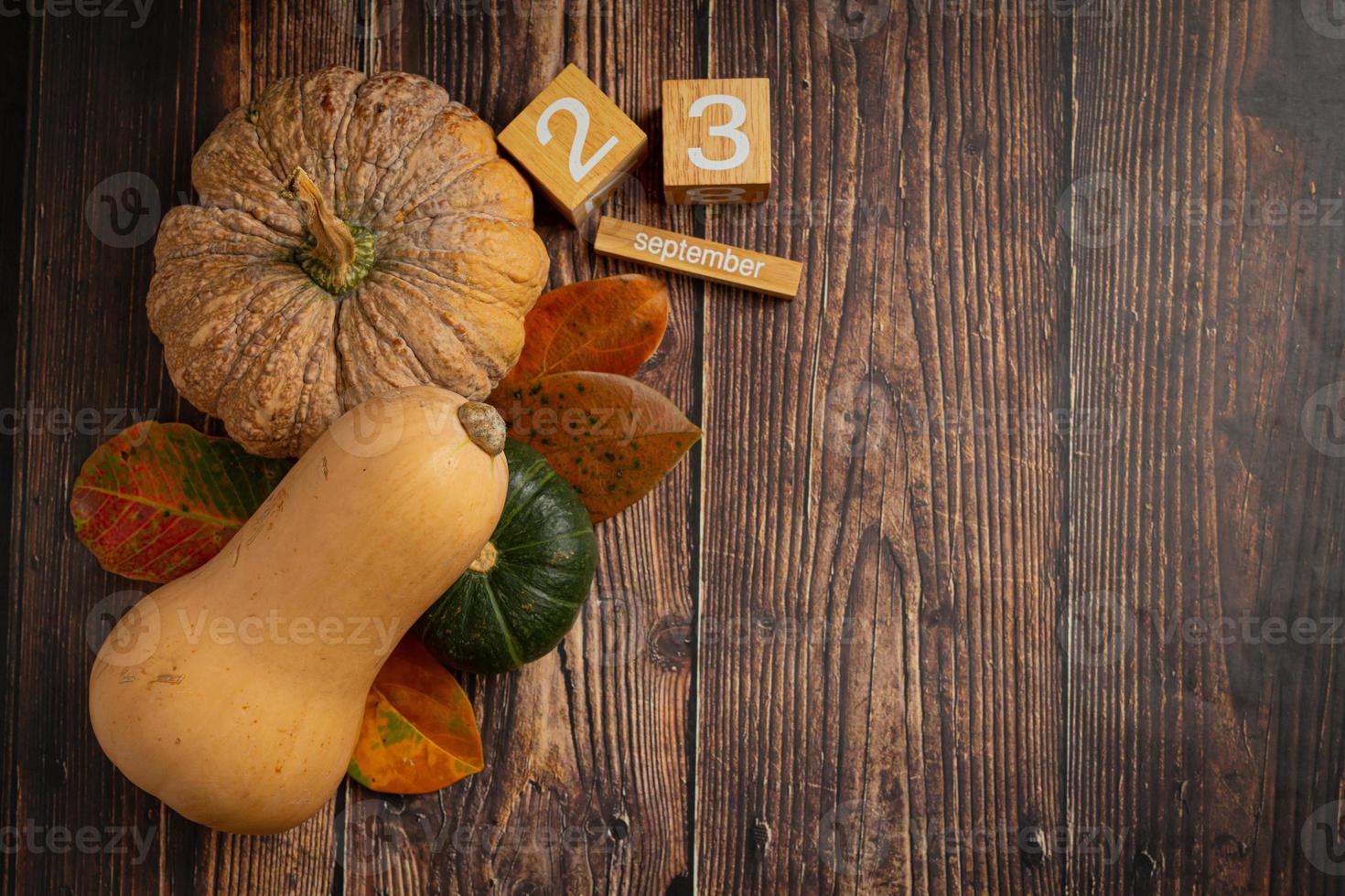 calabaza, hoja de arce y calendario colocados en un piso de madera, hola concepto de septiembre. foto