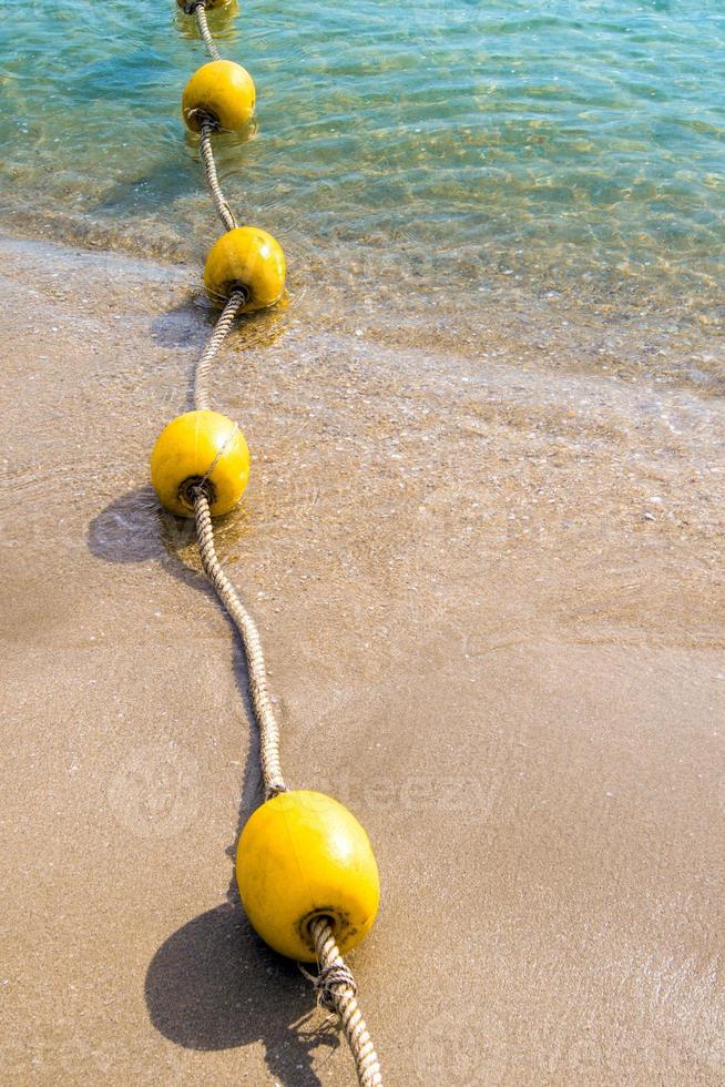 Floating buoy and rope dividing the area on the beach photo