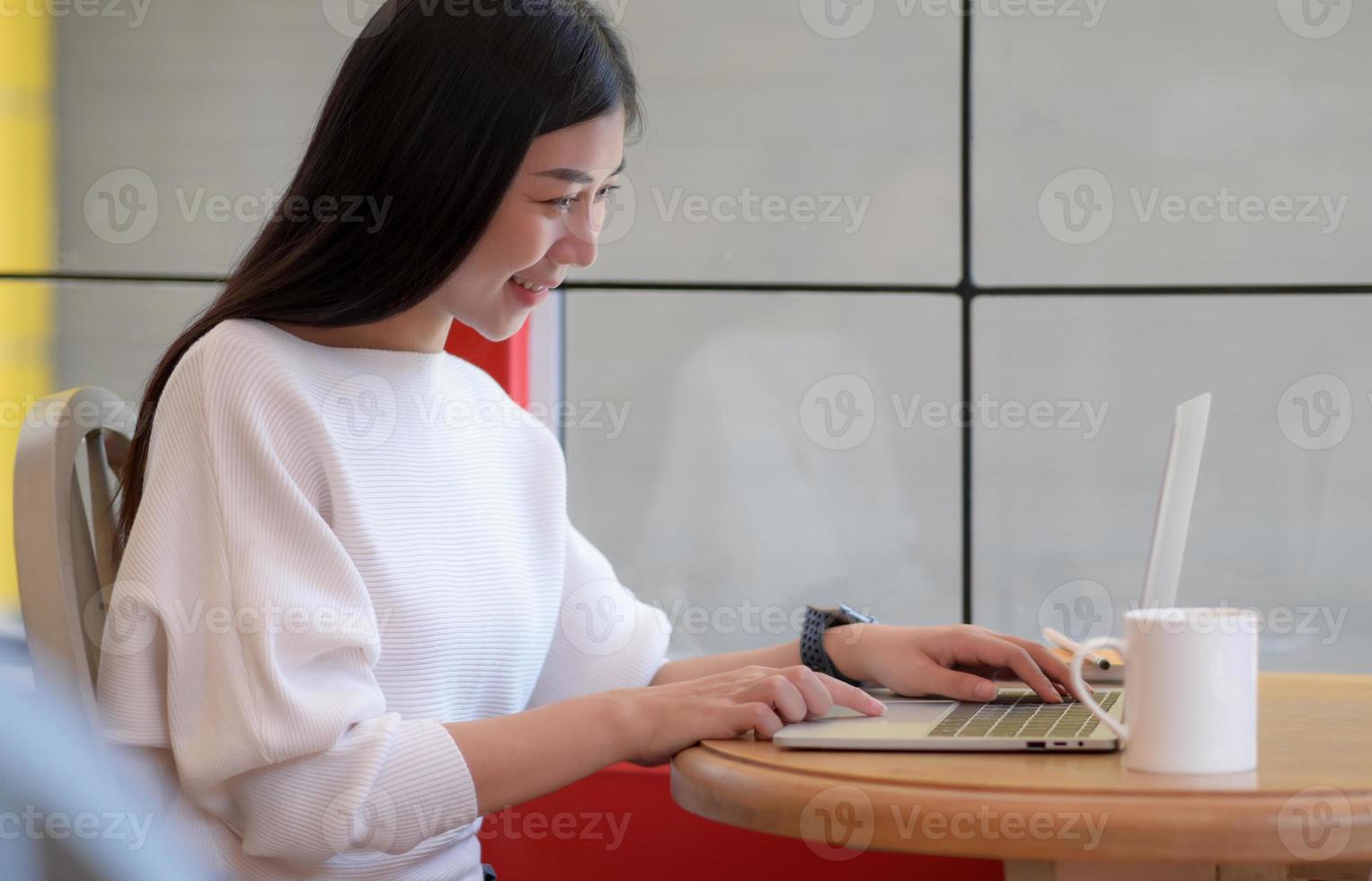joven estudiante universitario que usa una computadora portátil para charlar en línea con una sonrisa feliz. foto