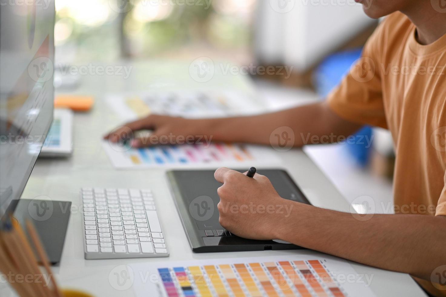 Professional graphic designers are working on digital boards with color charts on their desk. photo