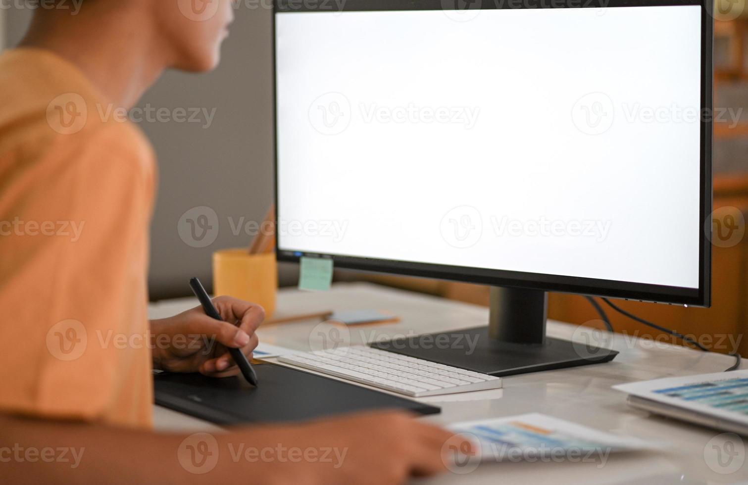 Graphic designer working on digital board with mockup computer monitor blank screen. photo