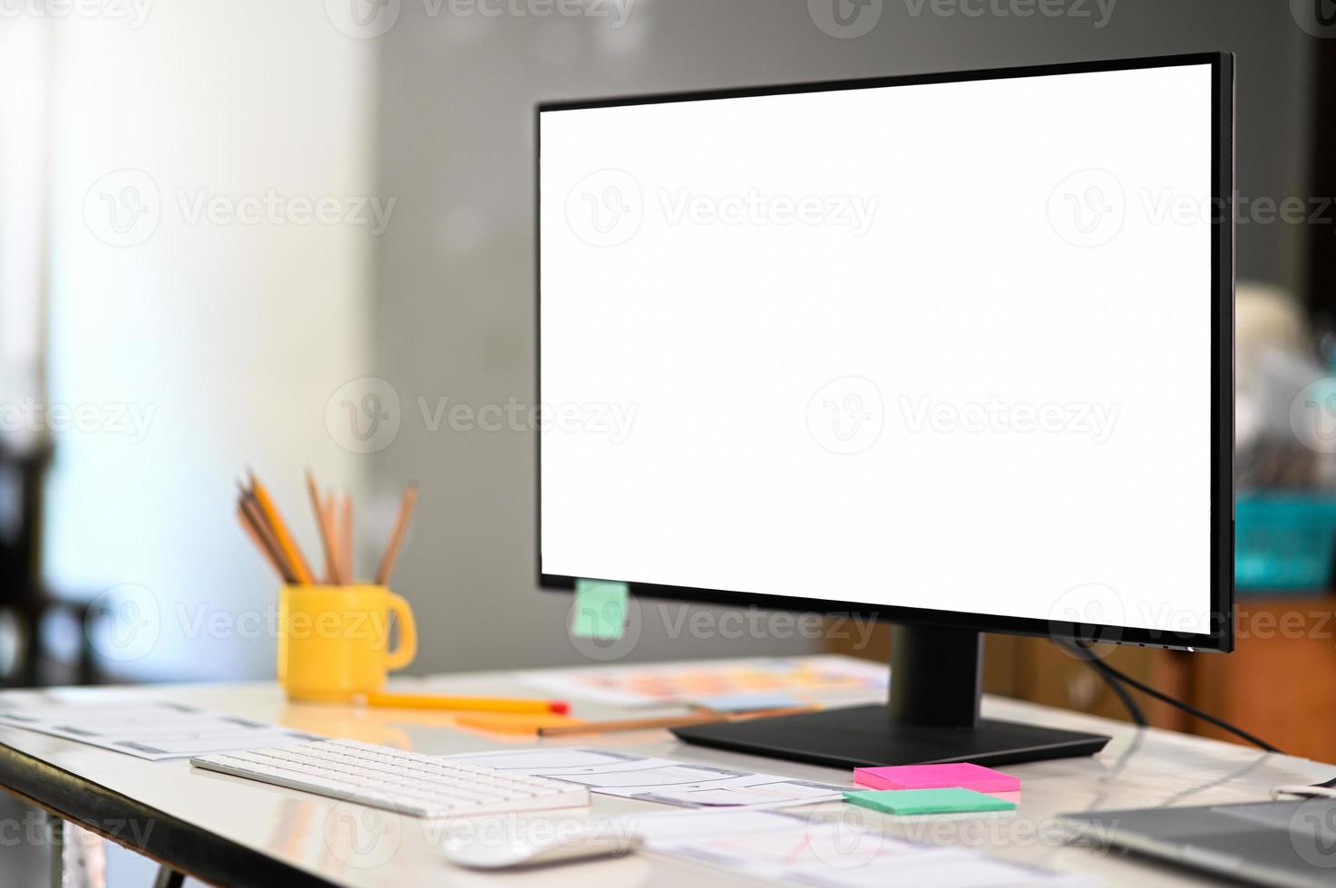 maqueta de computadora gran pantalla en blanco en un escritorio de diseñador profesional en una oficina cómoda. foto