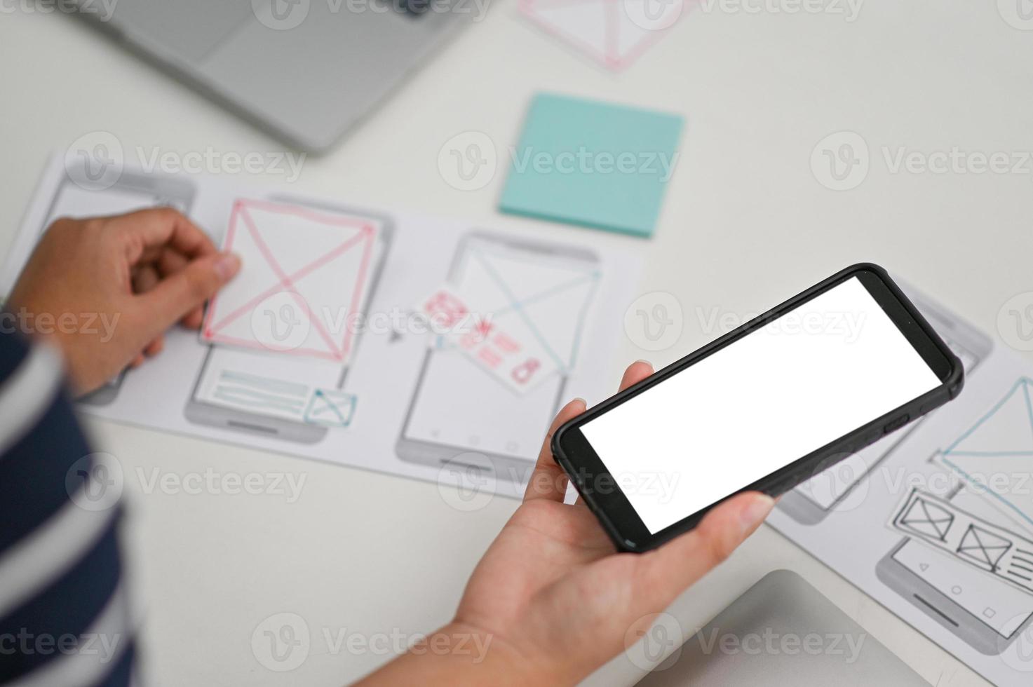 ux, diseñador de interfaz de usuario sosteniendo un teléfono inteligente y redactando un nuevo diseño. foto