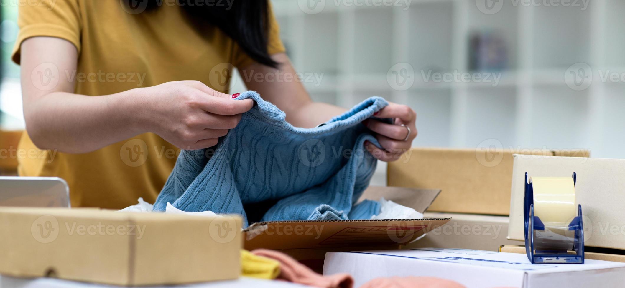 los vendedores en línea están revisando los suéteres de punto antes de empacarlos para el envío. foto