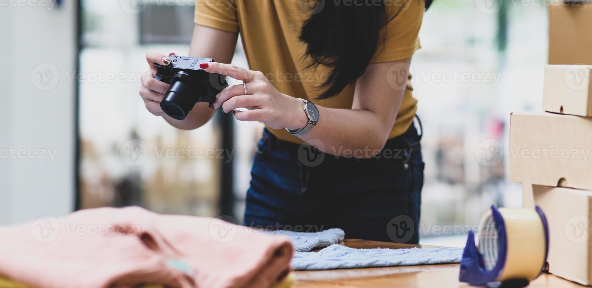 A woman uses a camera to take photos of sweaters to post online sales on the Internet.