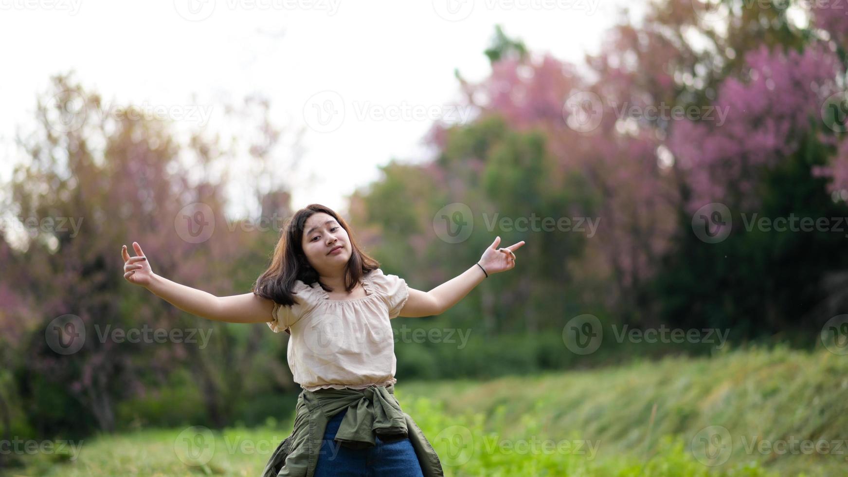 niña asiática sonríe con picardía y se vuelve hacia la cámara durante un recorrido por la naturaleza. foto