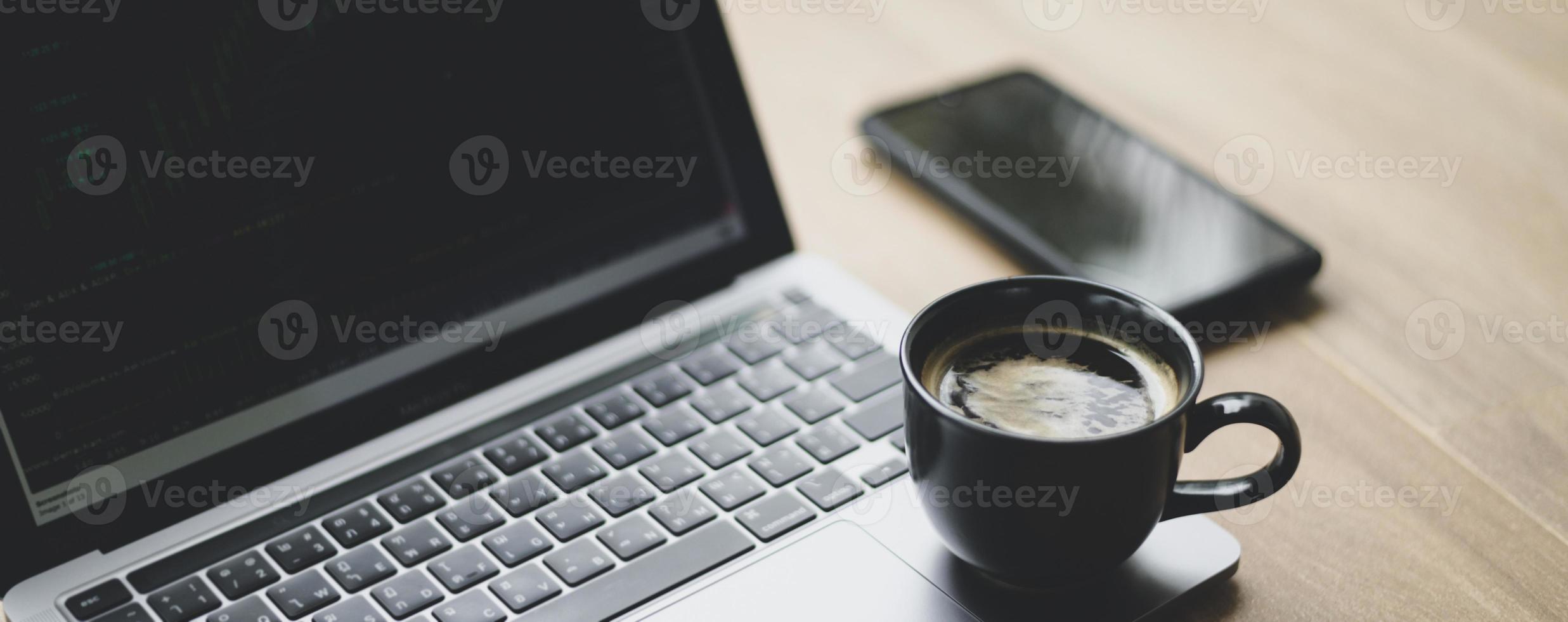 taza de café colocada en la computadora portátil con gráfico de acciones en la pantalla, primer plano. foto