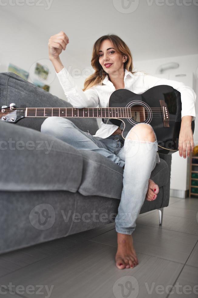 Una joven zurda con guitarra acústica. foto