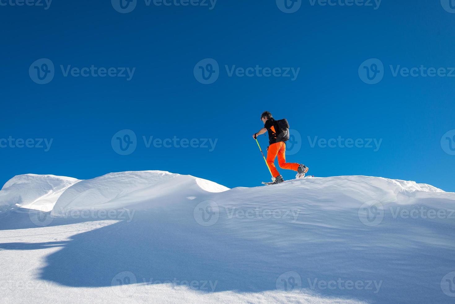 Un hombre esquiador alpino subir con esquís y pieles de foca en la cresta alpina foto