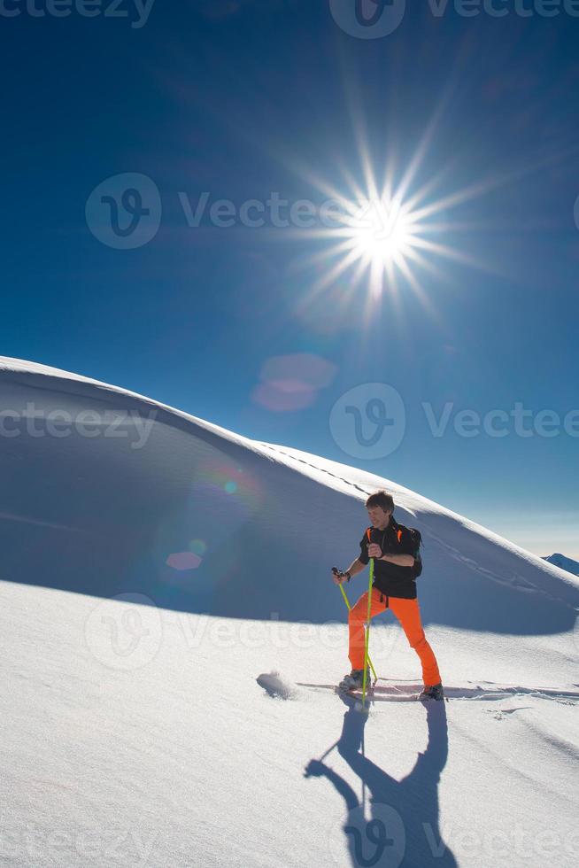 A man alpine skier climb on skis and sealskins in a strong sunny day photo