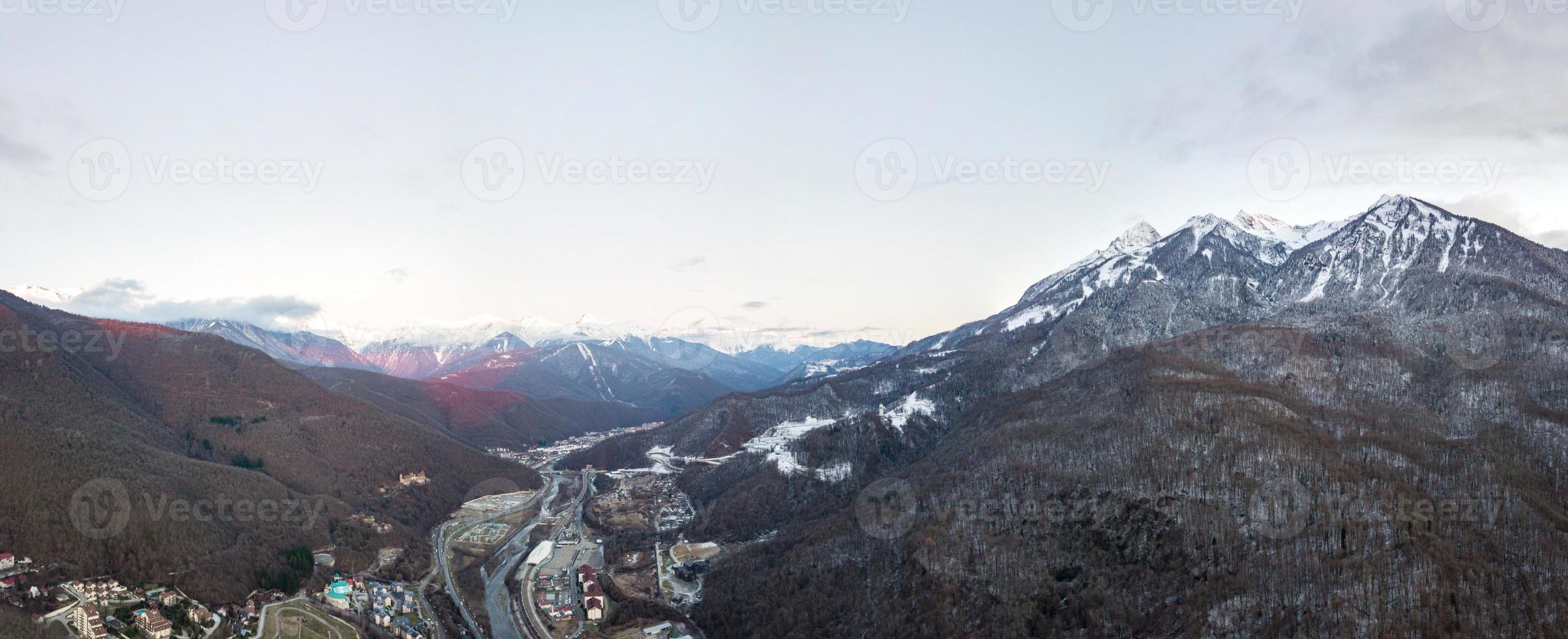 Vista aérea de krasnaya polyana al atardecer, montañas cubiertas de nieve. Rusia. foto