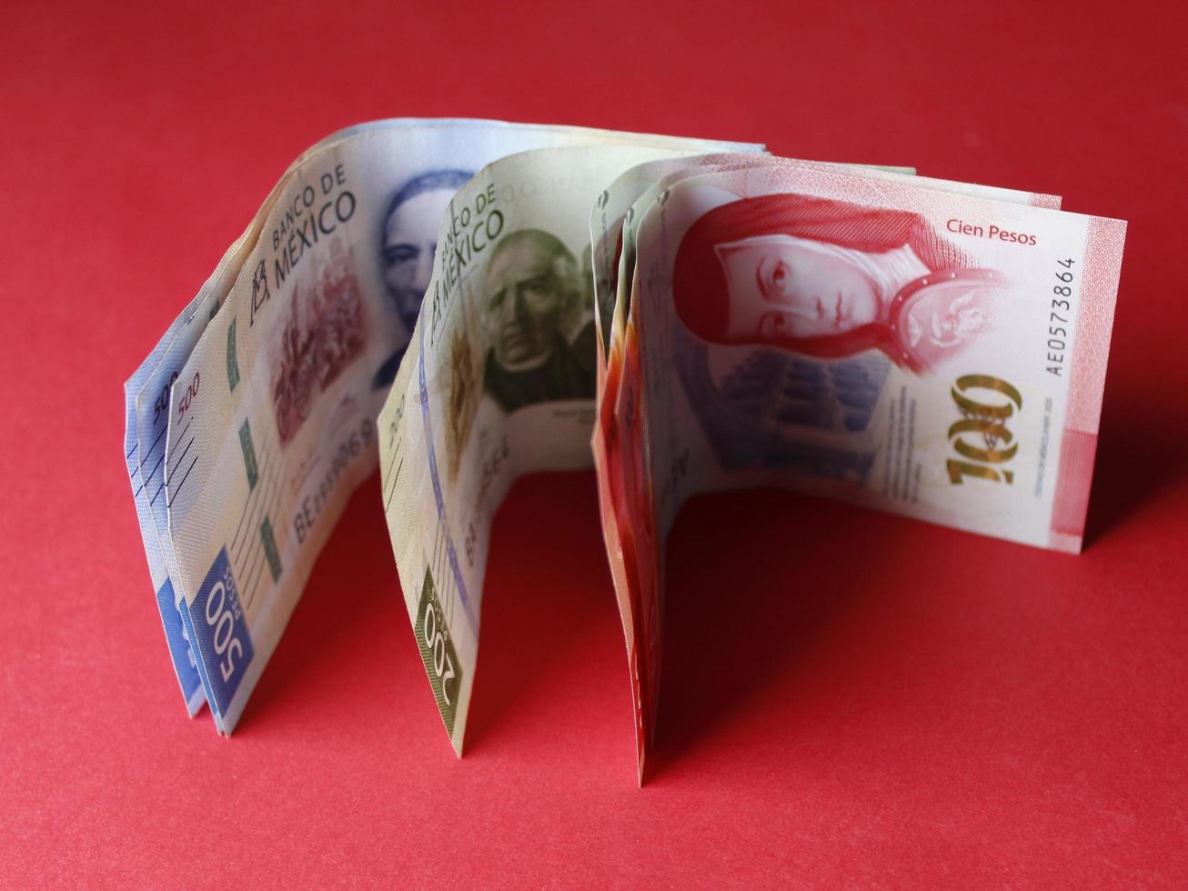 Rows of mexican banknotes of different denomination on the red background photo