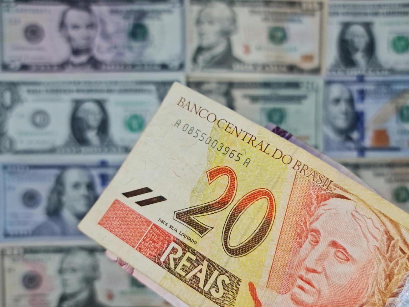 Approach to brazilian banknote of twenty reais and background with american dollar bills photo