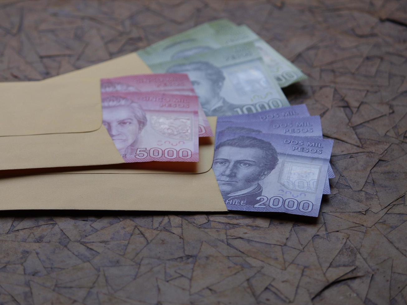 Billetes chilenos en sobres de papel amarillo sobre superficie marrón foto