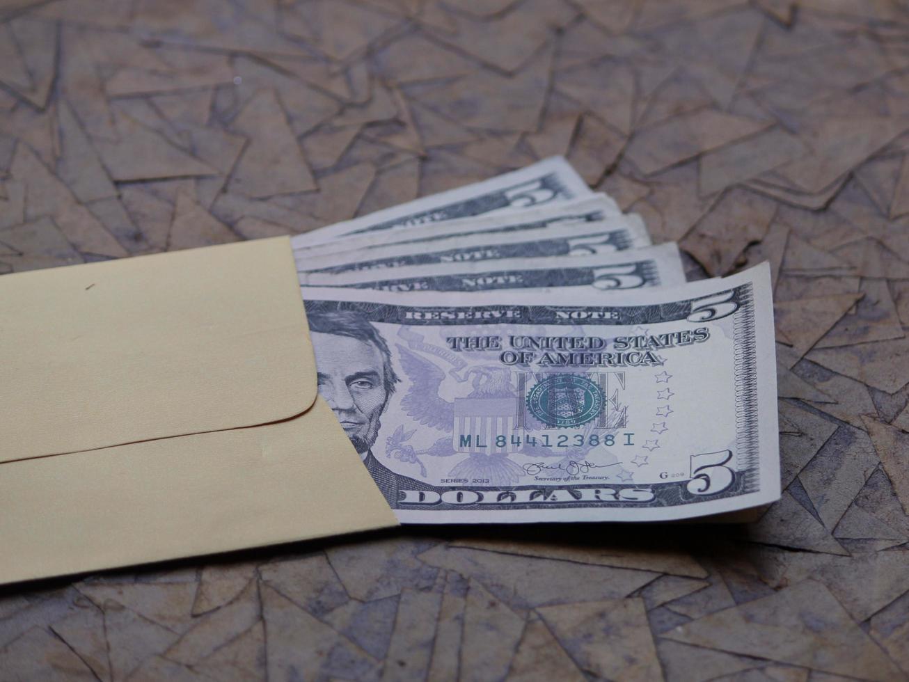 Billetes de dólares americanos en sobres de papel amarillo sobre superficie marrón foto