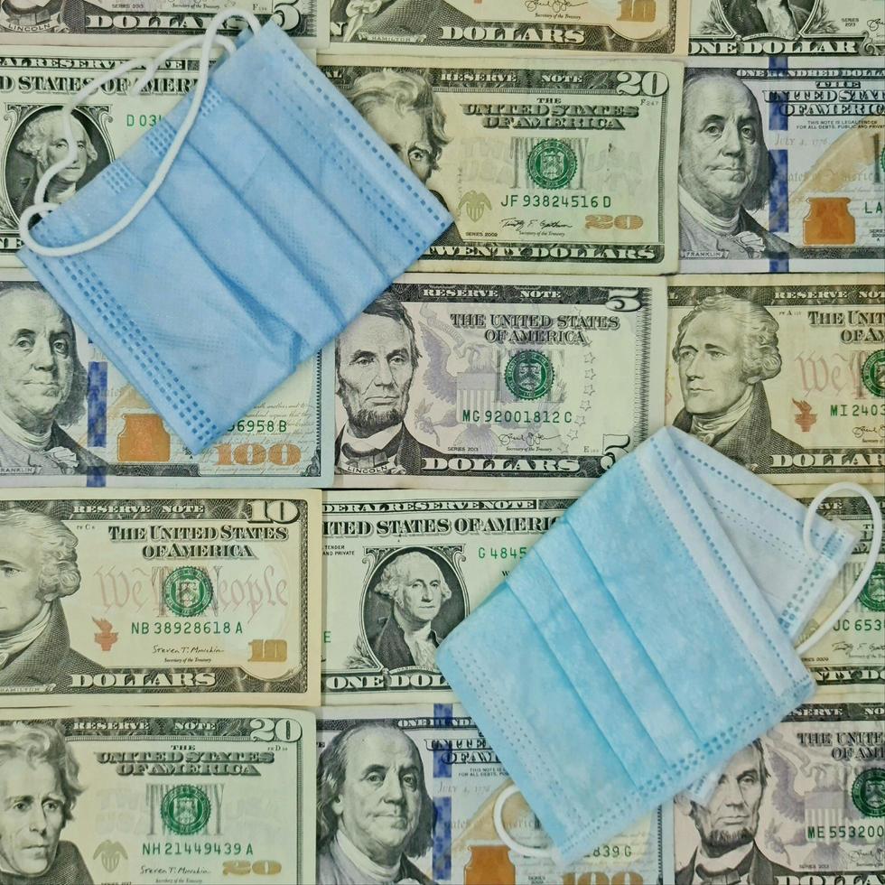 Disposable face masks and background with american dollar bills, view from above photo