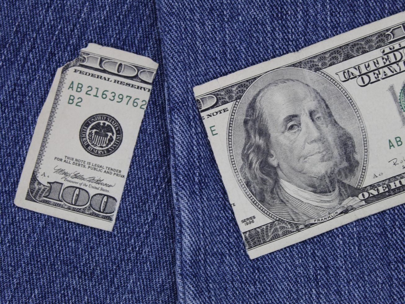 Broken american banknote of 100 dollars between blue denim fabric photo