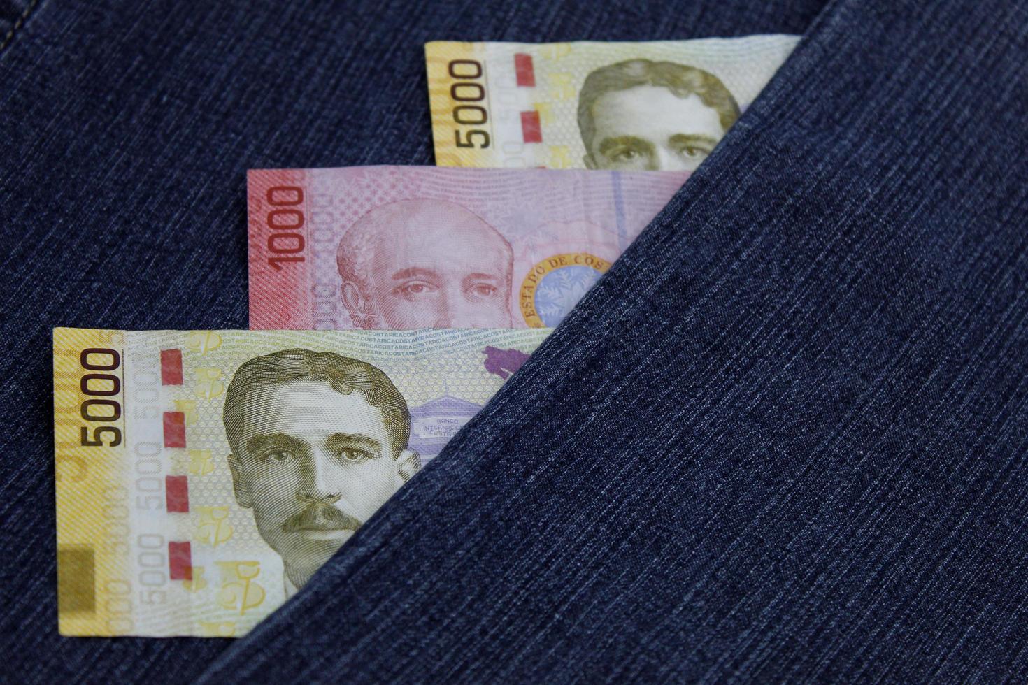 Billetes costarricenses apilados entre tela de mezclilla azul foto