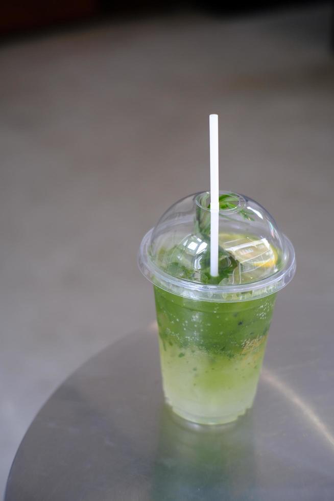 Iced matcha lemon soda on the table, Pouring green tea into a glass of honey lemon soda. photo