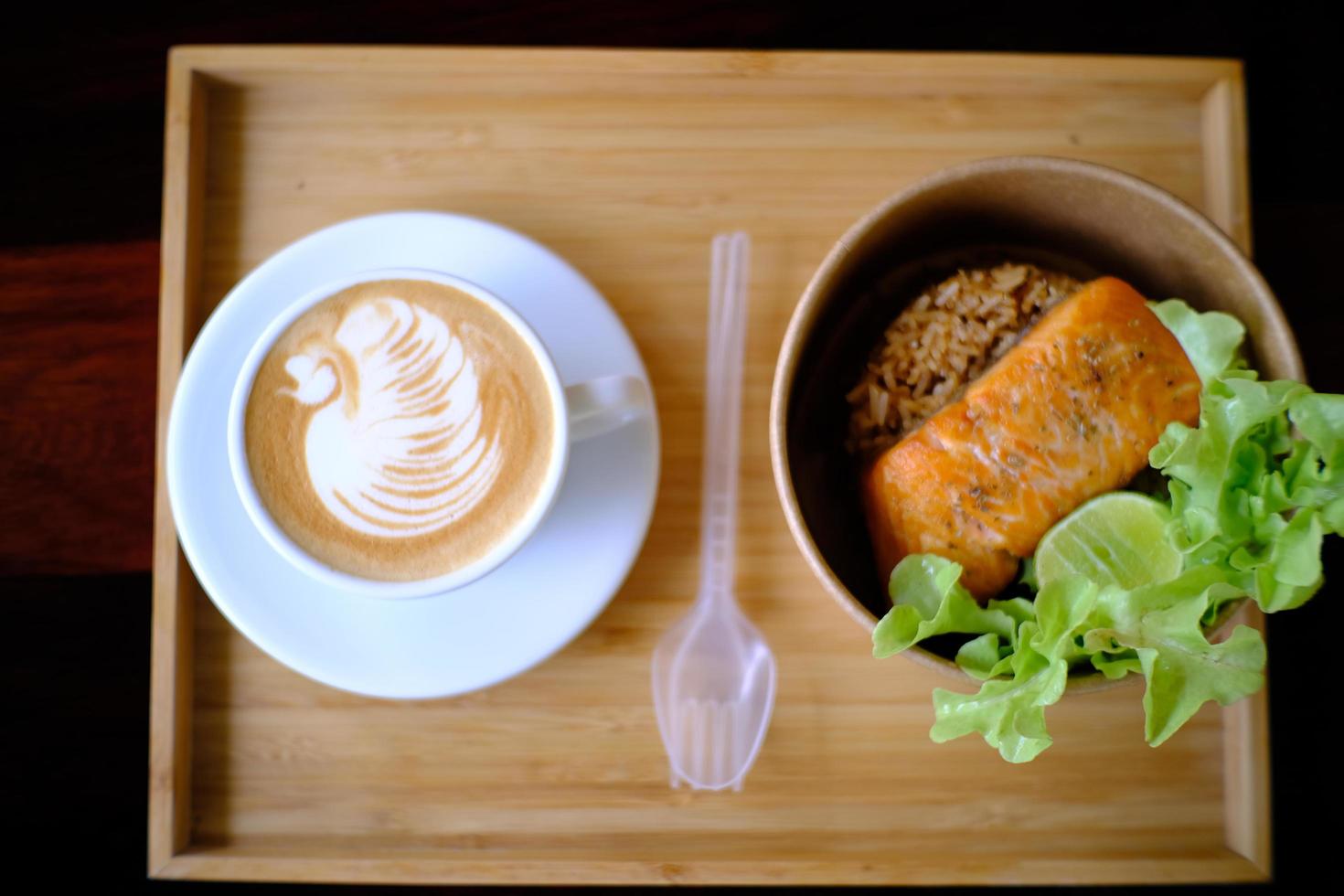 Coffee cup with latte art in a swan shape and Fried salmon steak photo