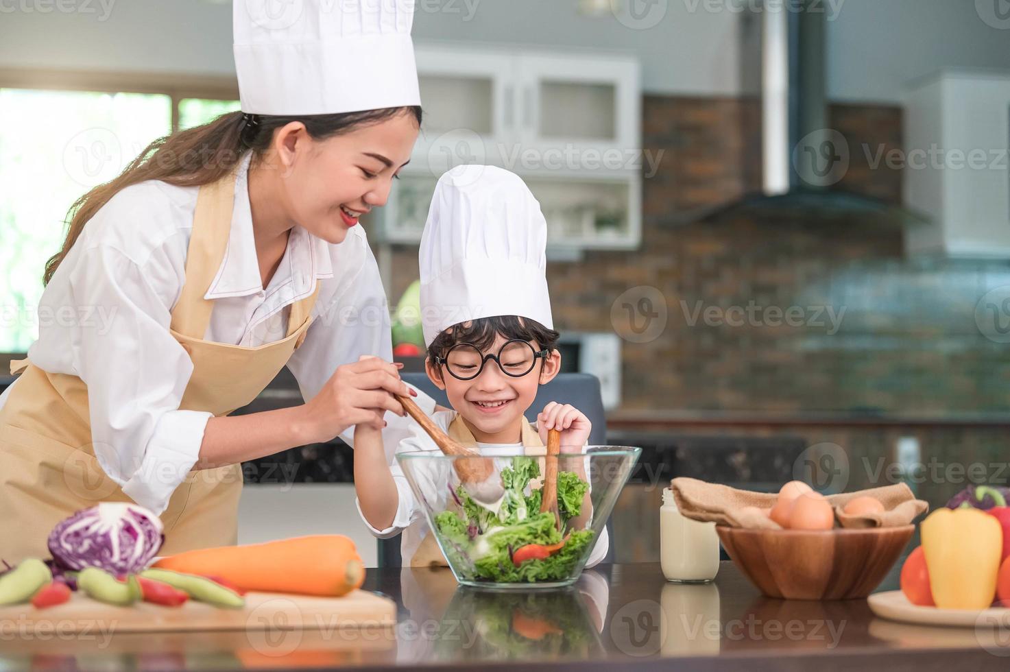 Feliz hermosa mujer asiática y lindo niño con anteojos se preparan para cocinar en la cocina de casa. estilos de vida de personas y familia. concepto de ingredientes y comida casera. vida de dos personas tailandesas foto