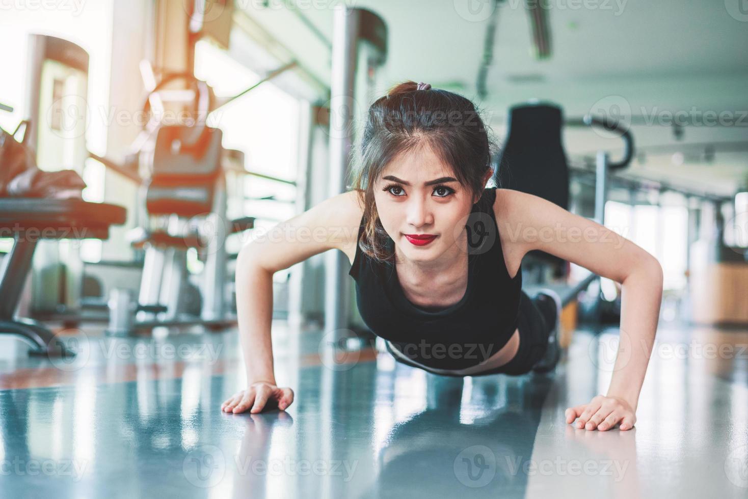 Asian woman fitness girl do pushing ups at fitness gym. Healthcare and Healthy concept. Training and Body build up theme. Strength and Beauty concept photo