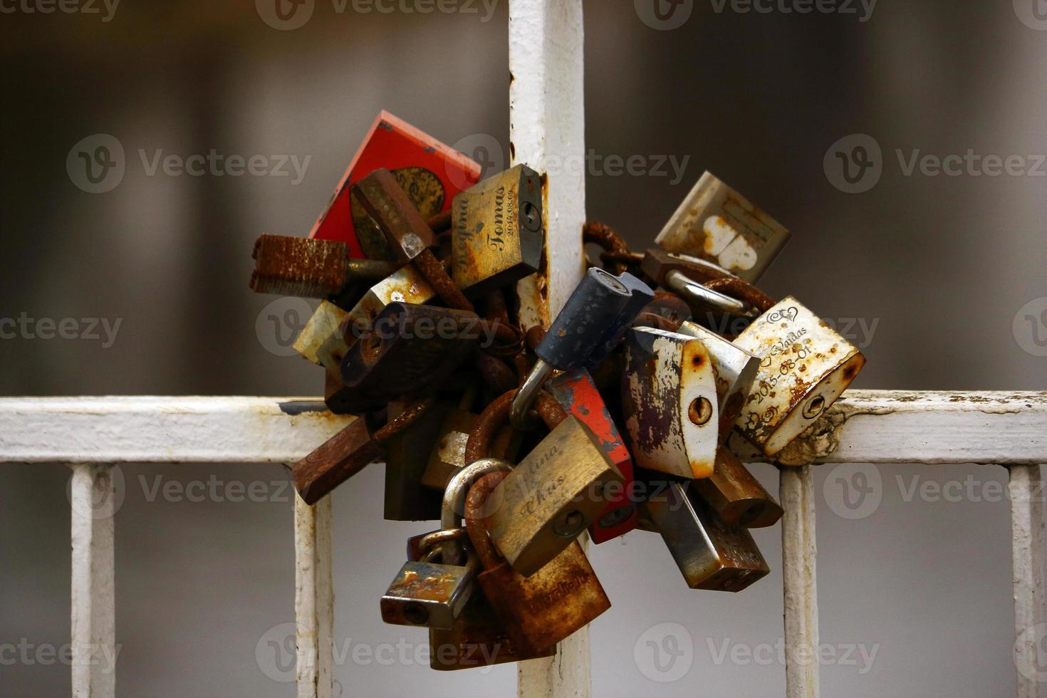 A bunch of rusty wedding padlocks hanging on bridge handrail photo