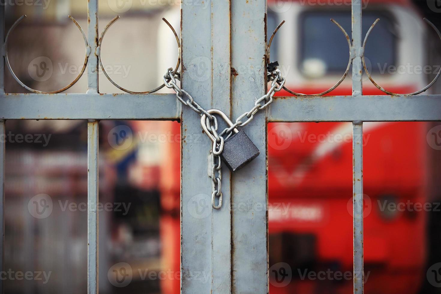 Candado cerrado colgando de la cadena en la puerta cerrada al ferrocarril foto